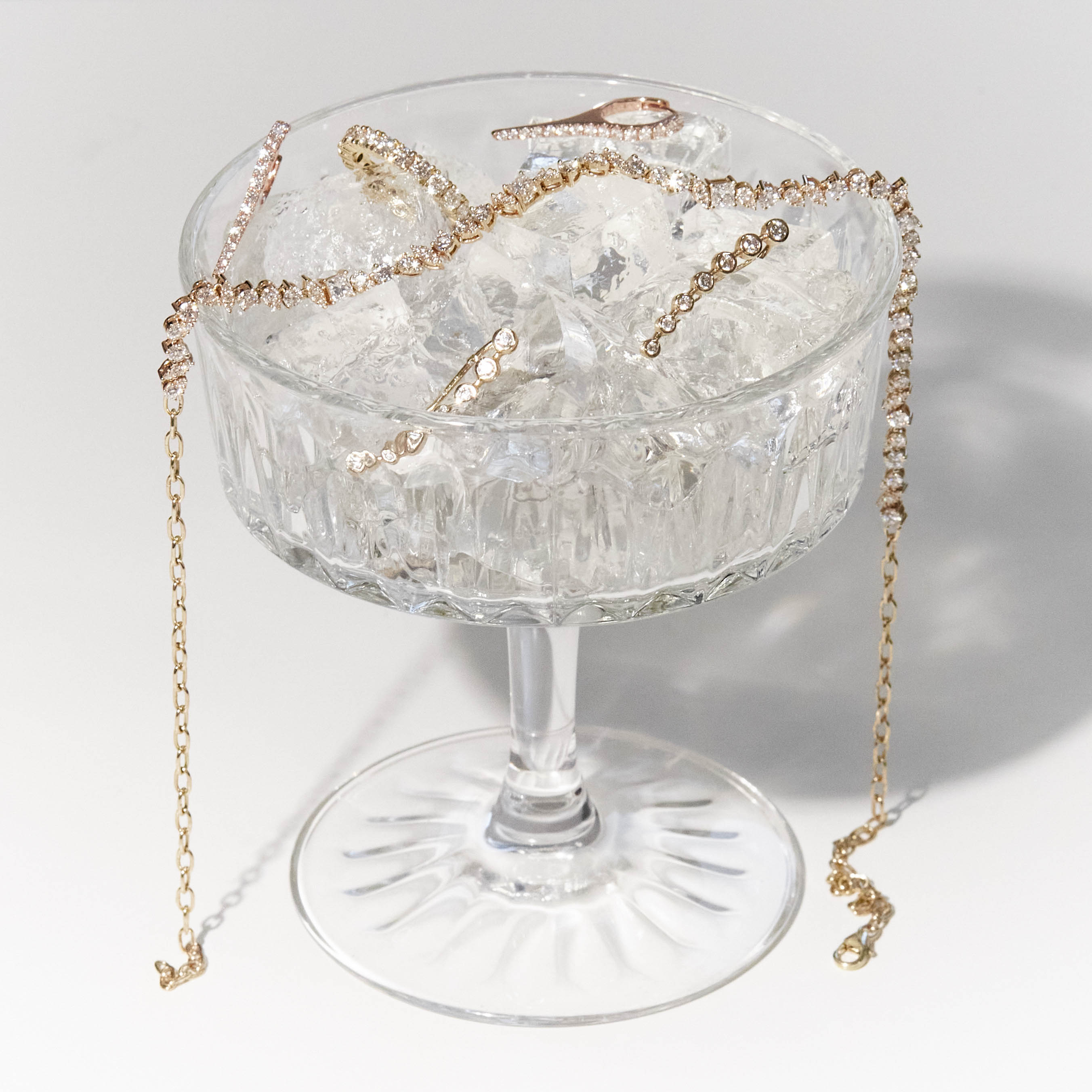 A cocktail glass with the perfect brew in it, diamond jewellery of all sorts on ice, earrings, choker and a eternity ring. 
