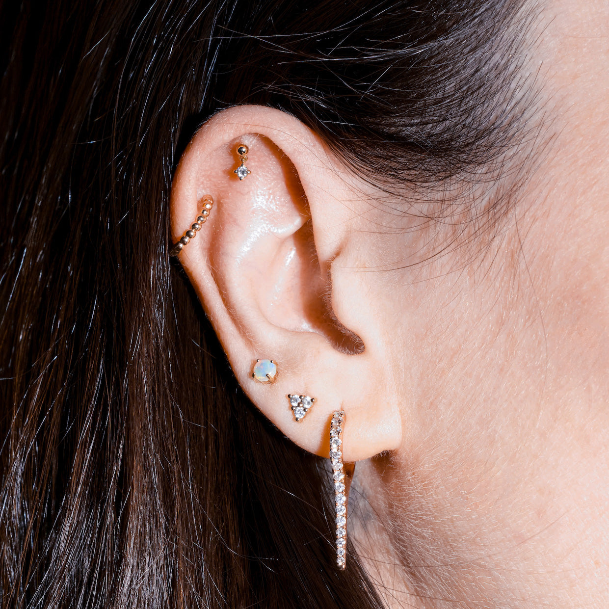 Close-up of an ear with multiple diamond earrings on a blurred background