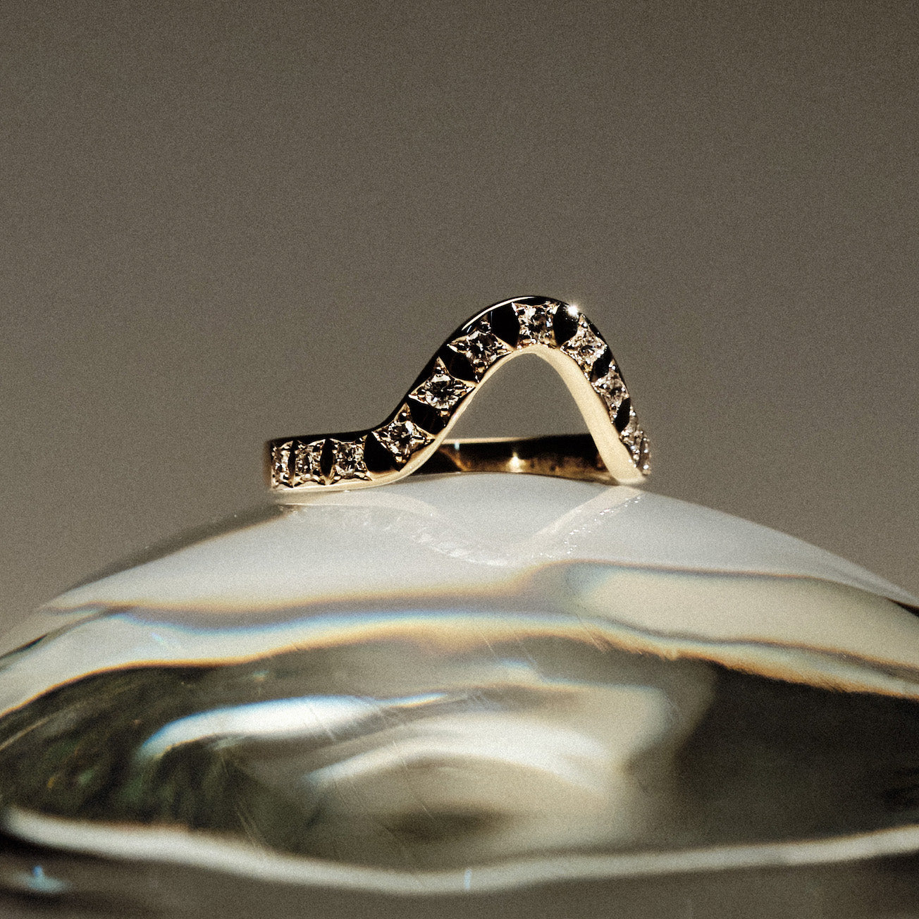 Yellow gold 2.5 mm band ring with 13 round diamonds  diamonds on a gray background.