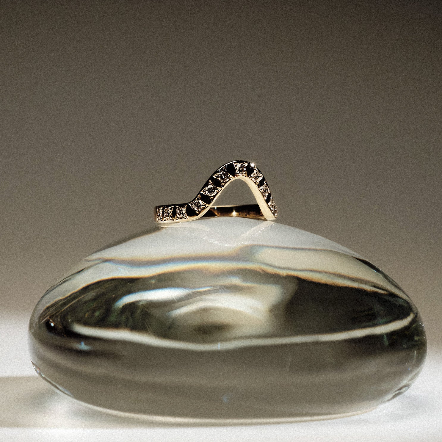 Yellow gold 2.5 mm band ring with 13 round diamonds  diamonds on a glass ball against a gray background.