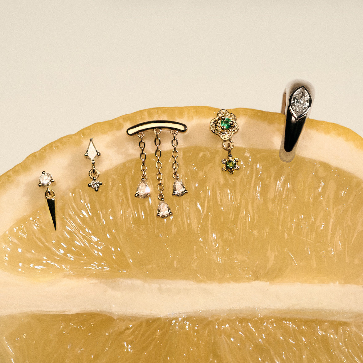Gold earrings, Teardrop Diamonds Chandelier stud, The Floating Kite Diamond Stud, The Floating Gold Icicle Stud, The Marquise Earcuff, on a lemon with a neutral backgrounda.
