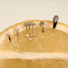 Gold earrings, Teardrop Diamonds Chandelier stud, The Floating Kite Diamond Stud, The Floating Gold Icicle Stud, The Marquise Earcuff, on a lemon with a neutral backgrounda.