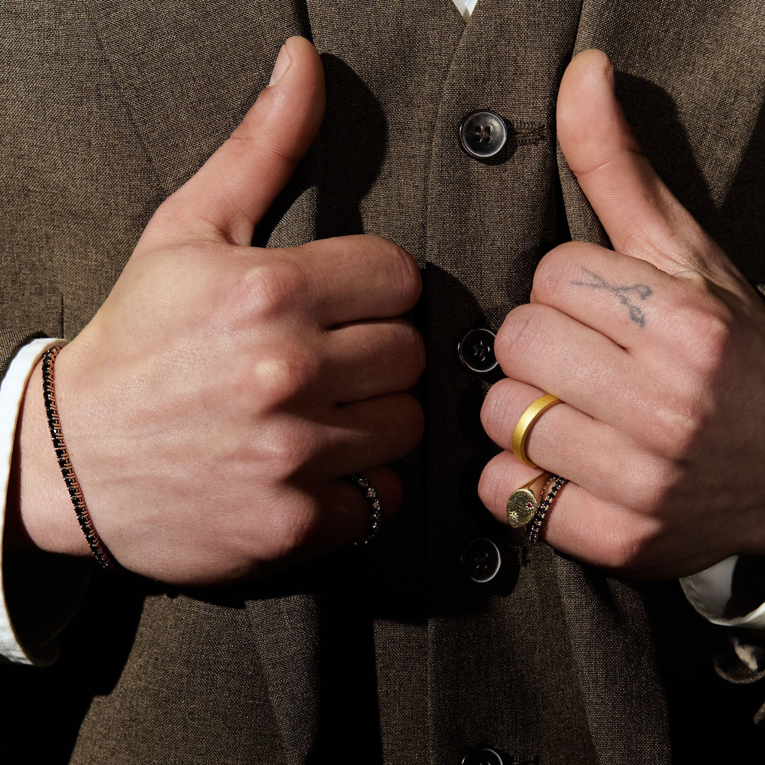 Close-up of hands with gold and precious stones rings on a brown textured background
