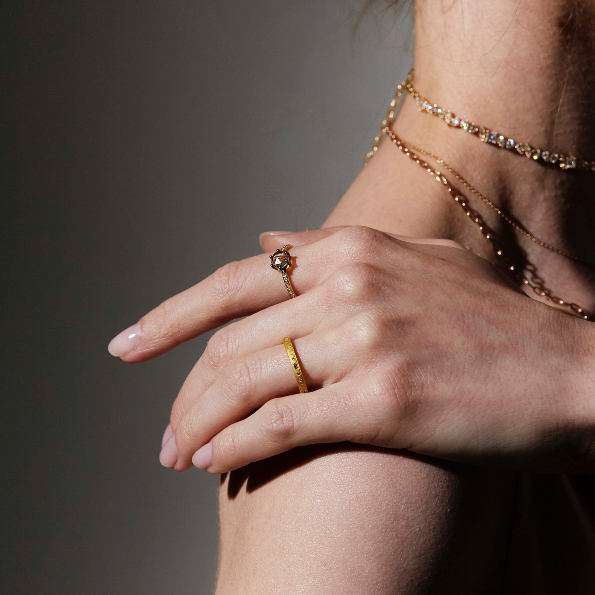Close-up of a hand wearing gold rings with a neutral background