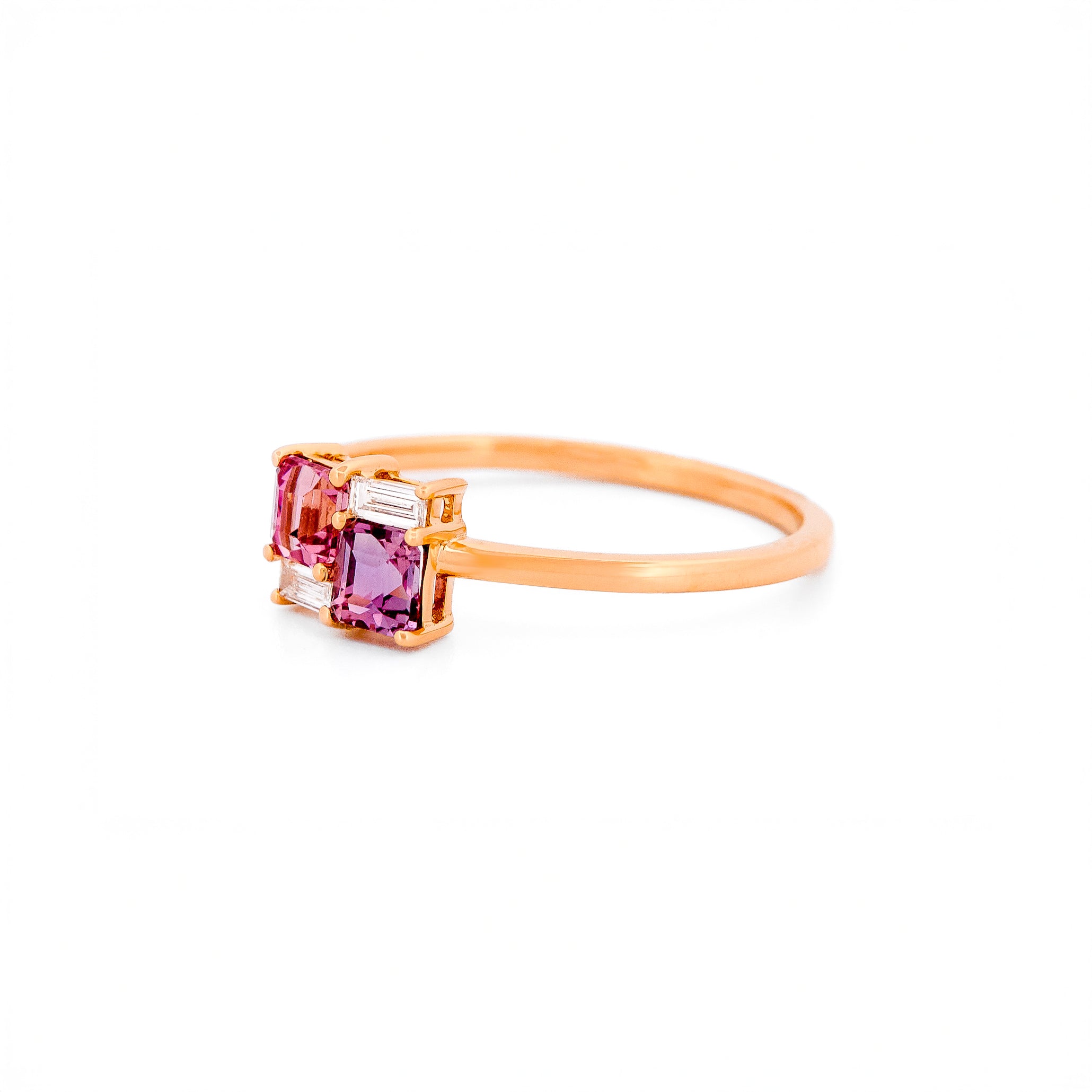 Gold ring with two pink sapphires and two diamonds on a white background.
