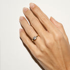 Hand wearing a gold ring with a solitaire diamond on a light background