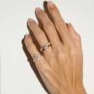 Hand wearing two diamond rings on a light background