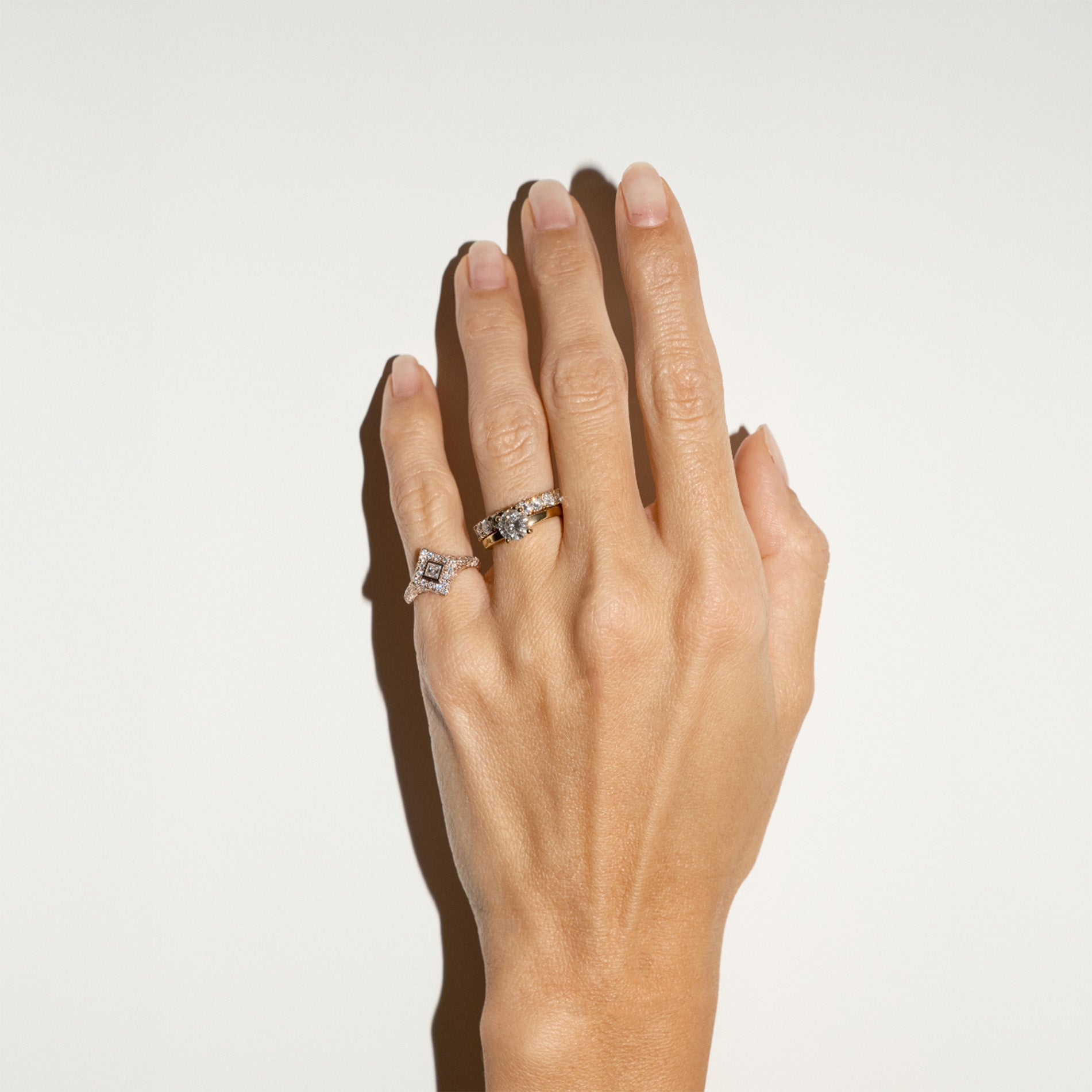 Solitaire gold ring with a 1 ct natural diamond, an eternity diamond band and a kite diamond pinky ring on hand