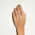 Hand wearing a diamond ring on a plain background
