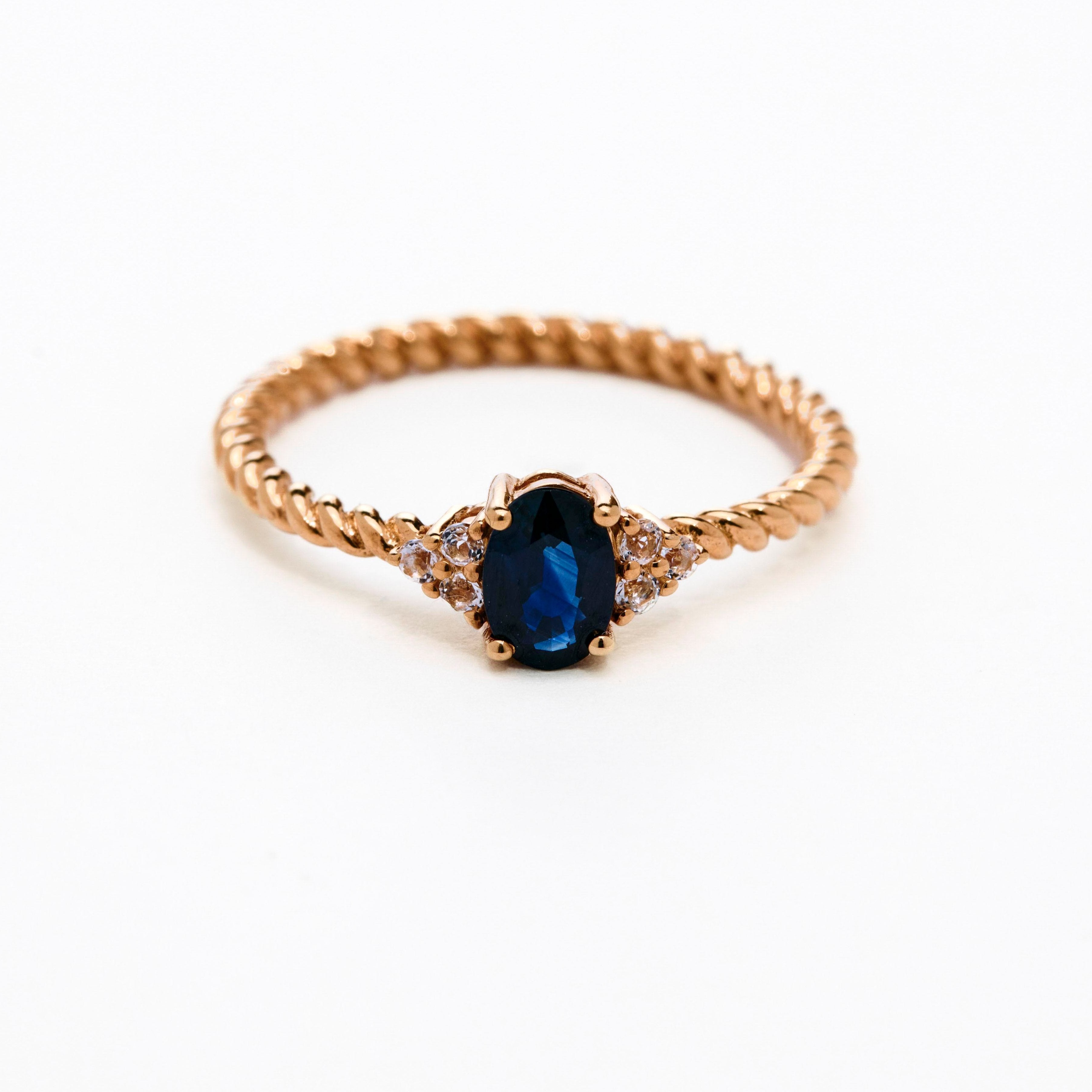 elegant oval blue sapphire ring with diamonds side cluster and a twisted band 