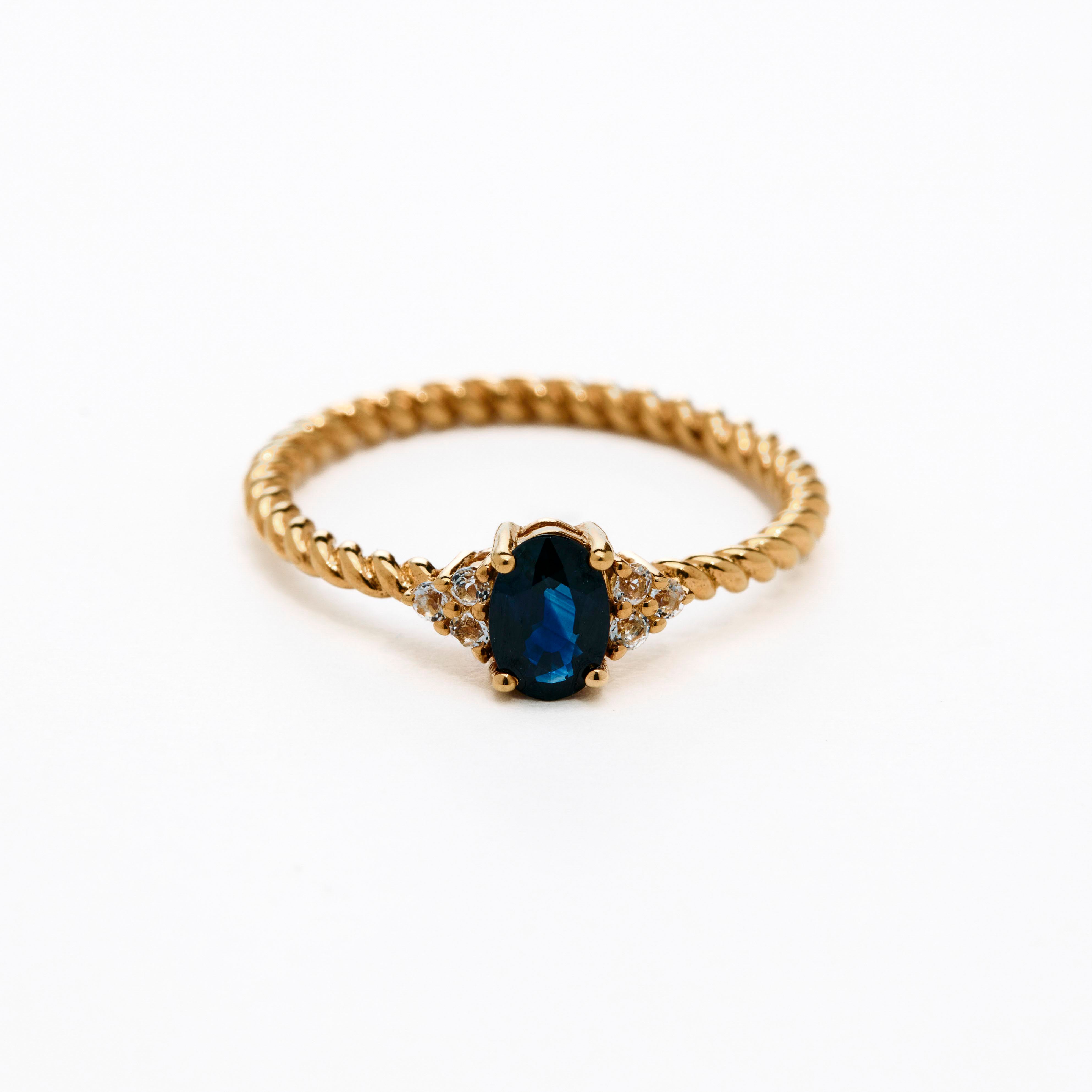 elegant oval blue sapphire ring with diamonds side cluster and a twisted band 