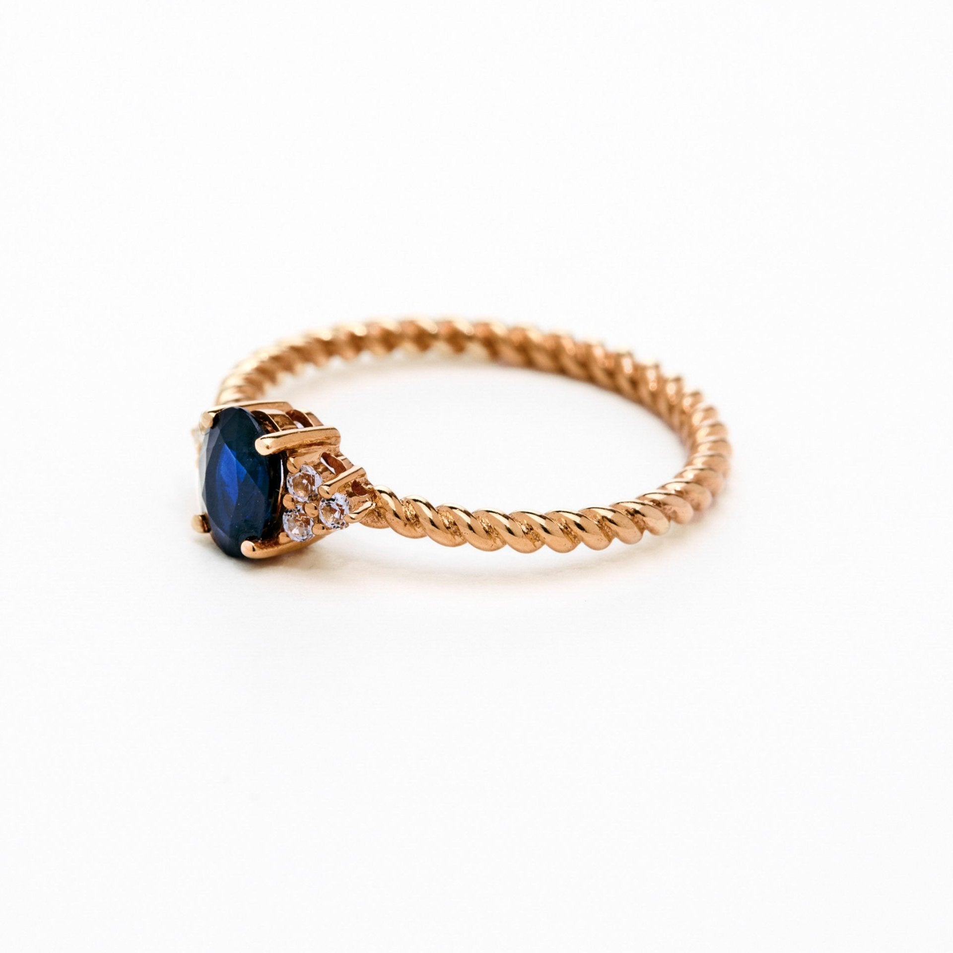 elegant oval blue sapphire ring with diamonds side cluster and a twisted band 
