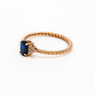 elegant oval blue sapphire ring with diamonds side cluster and a twisted band 