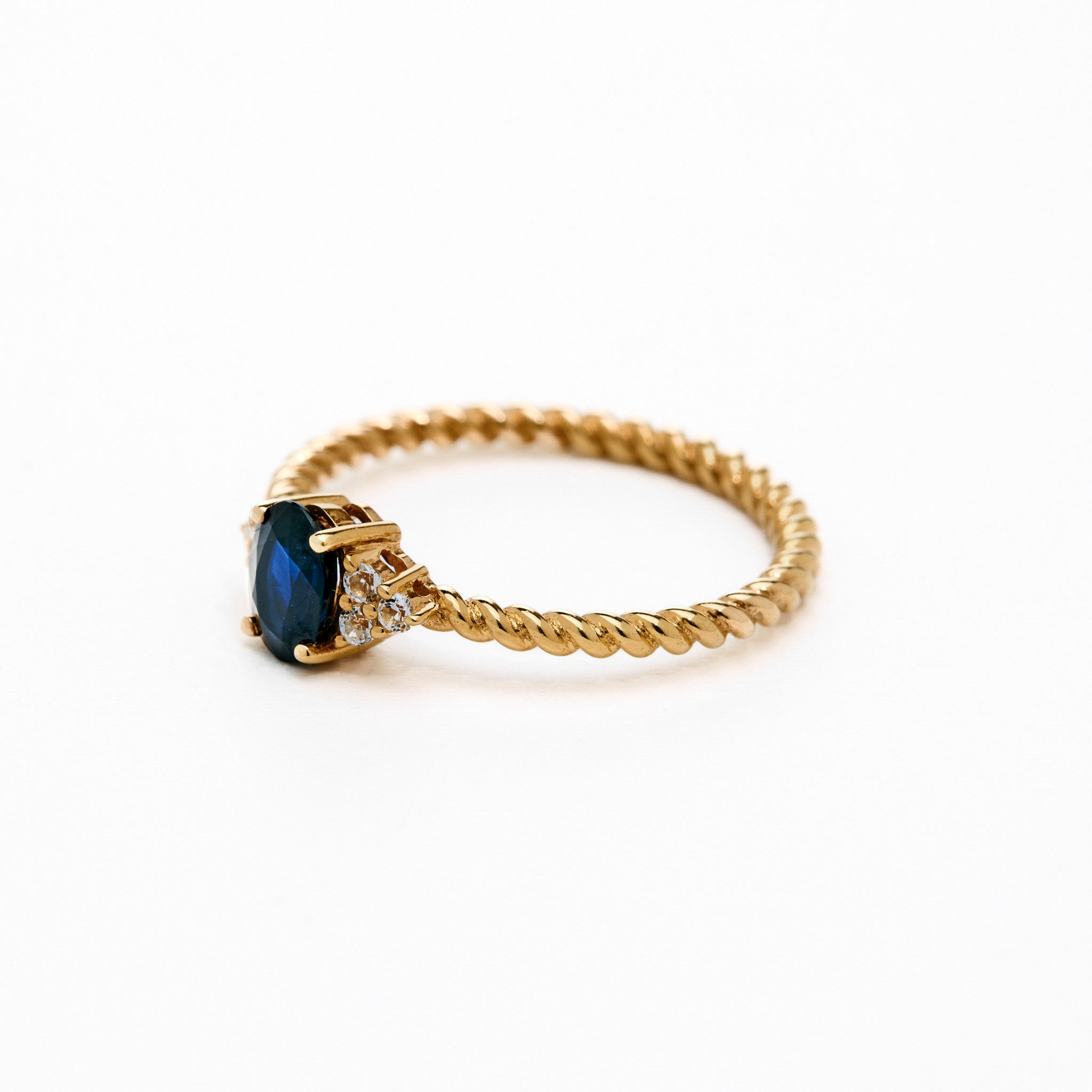 elegant oval blue sapphire ring with diamonds side cluster and a twisted band 