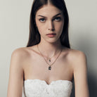 Woman wearing a strapless white lace dress with jewelry, a necklace with 14k gold heart plates on a neutral background