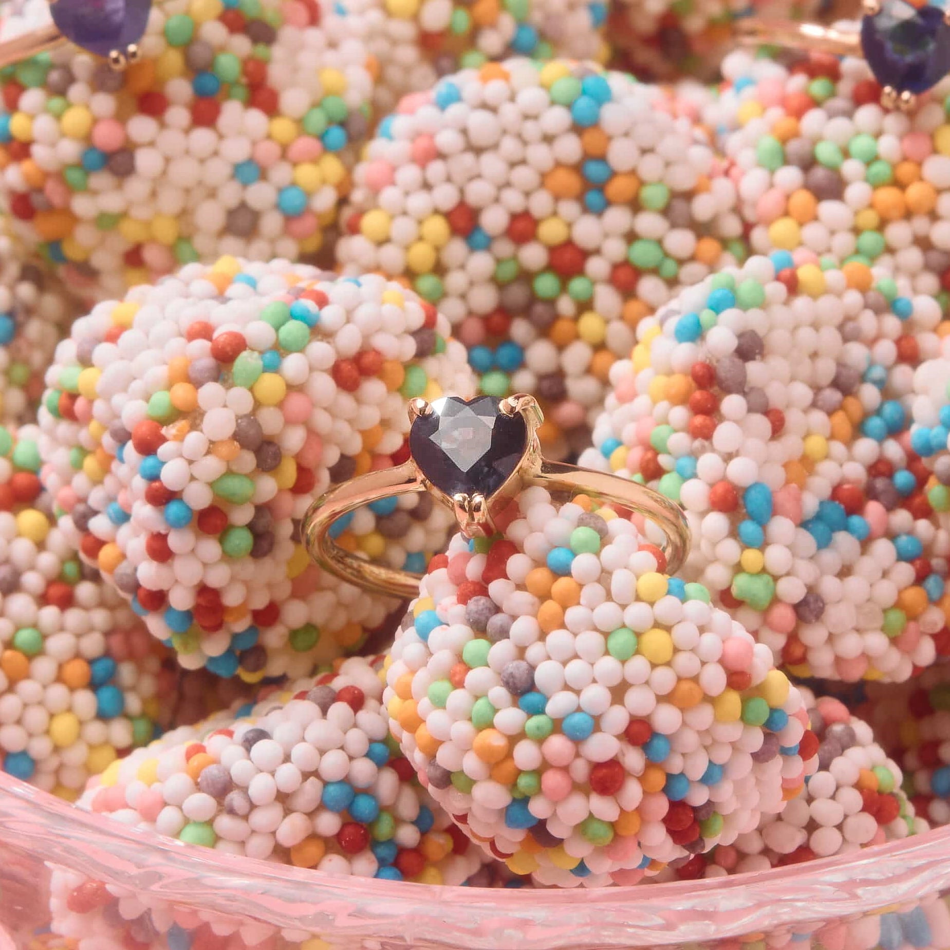 a sapphire heart ring in yellow gold between colourful candies