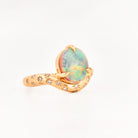 Yellow Gold ring with an australian opal centrestone on a white background.