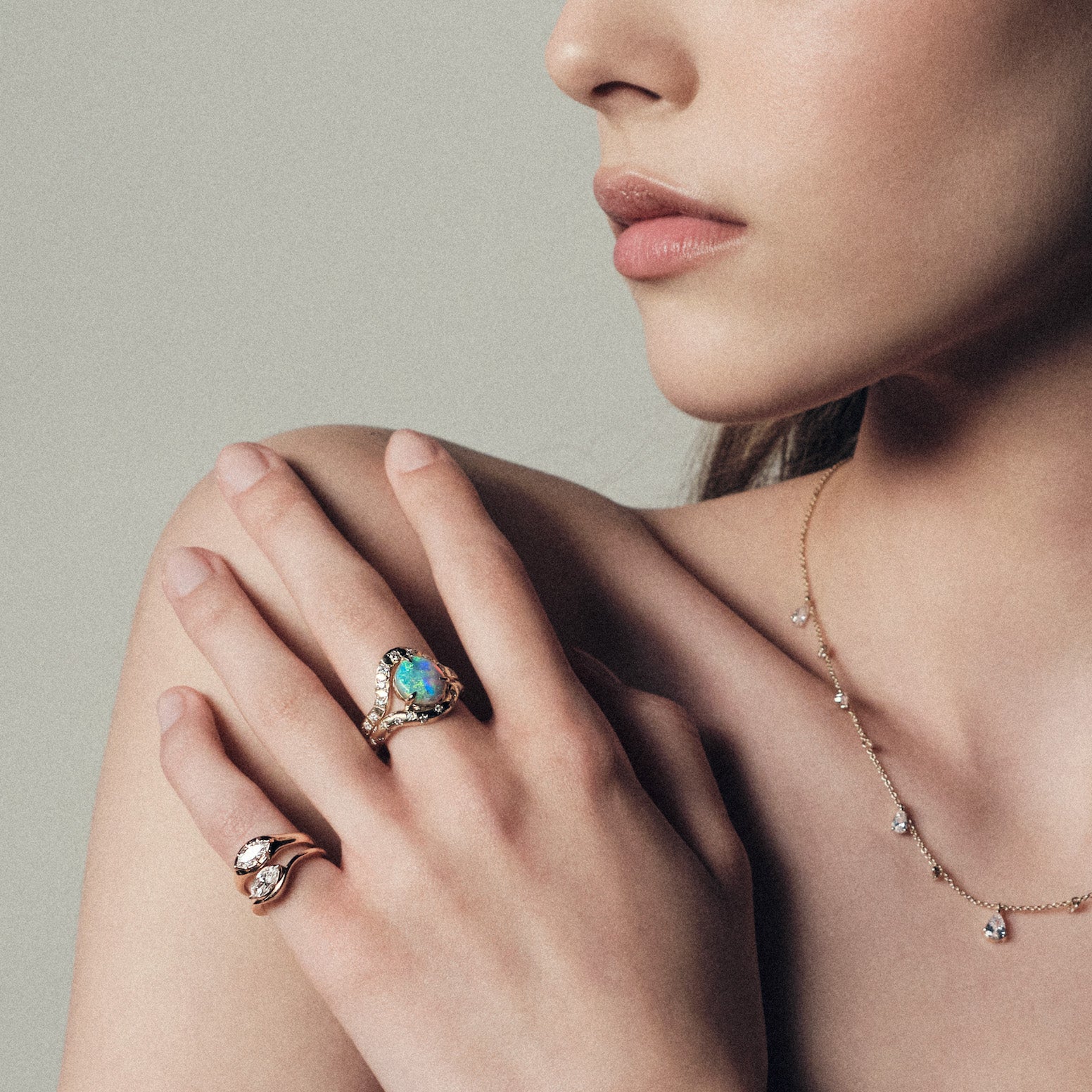 Close-up of a woman's hand wearing an opal ring with a neutral background.