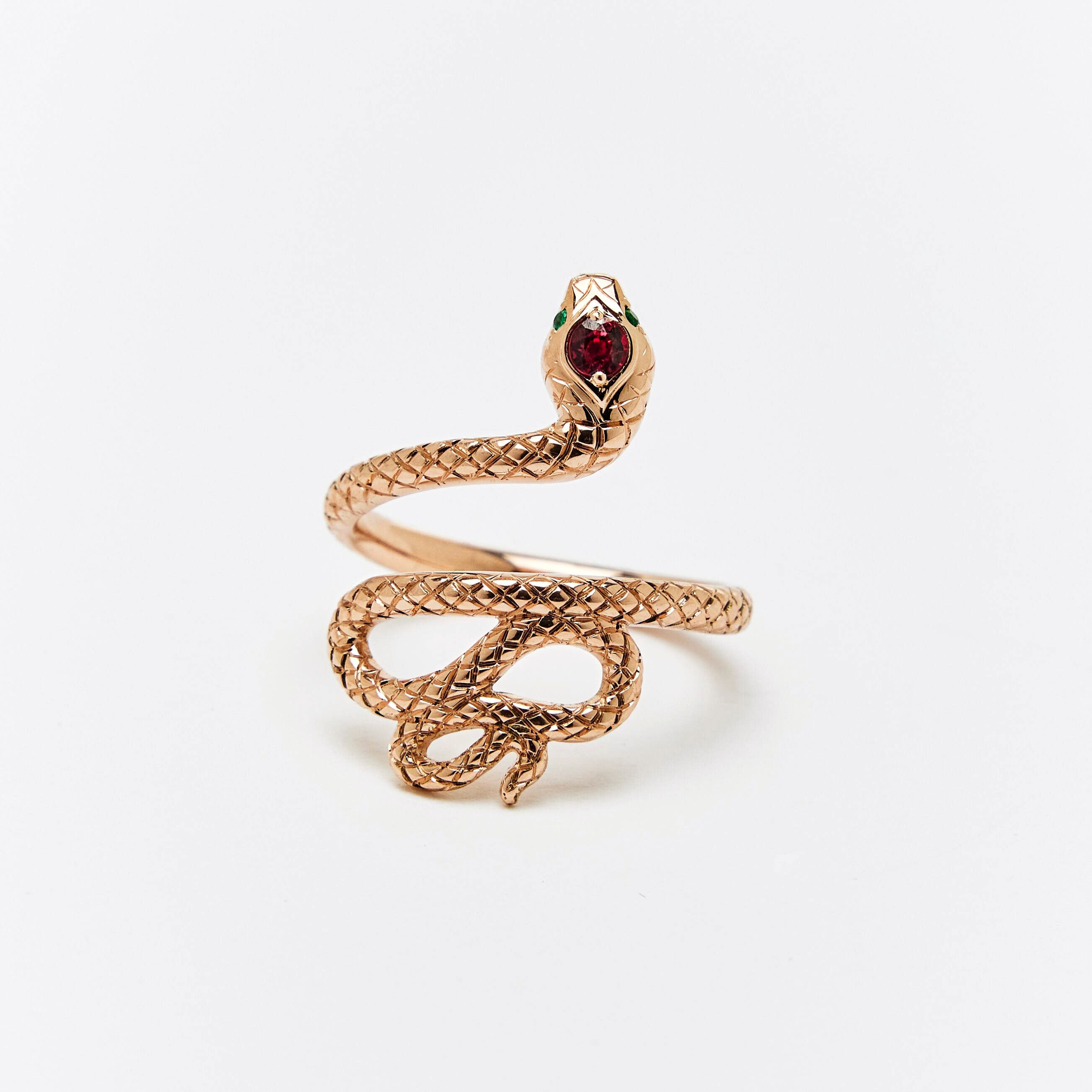 A snake ring with a red sapphire headstone and emerald eyes