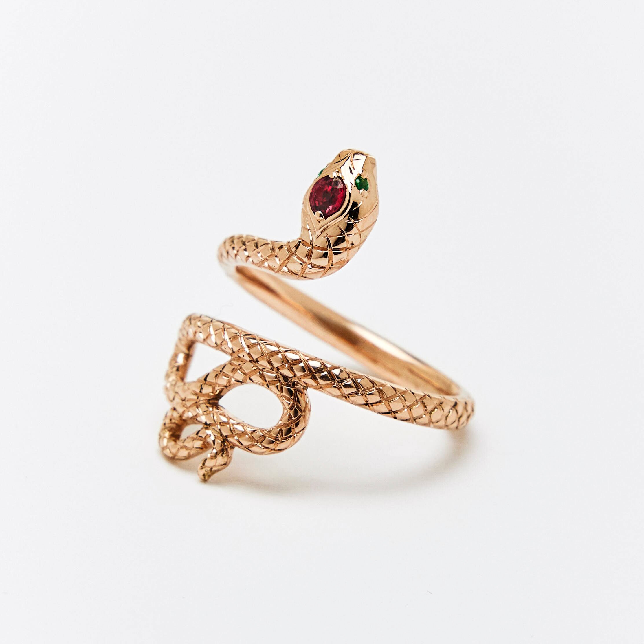 A snake ring with a red sapphire headstone and emerald eyes