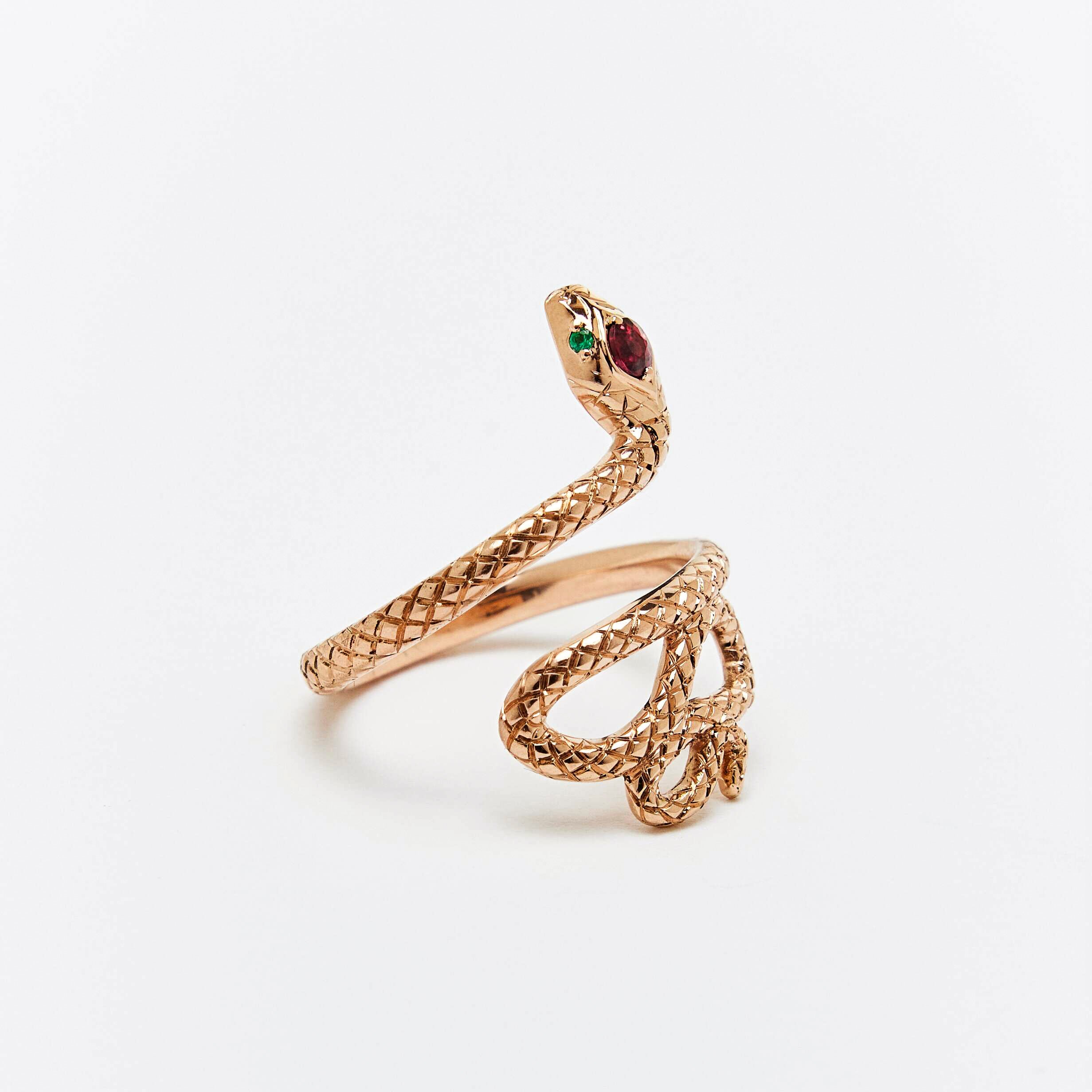 A snake ring with a red sapphire headstone and emerald eyes