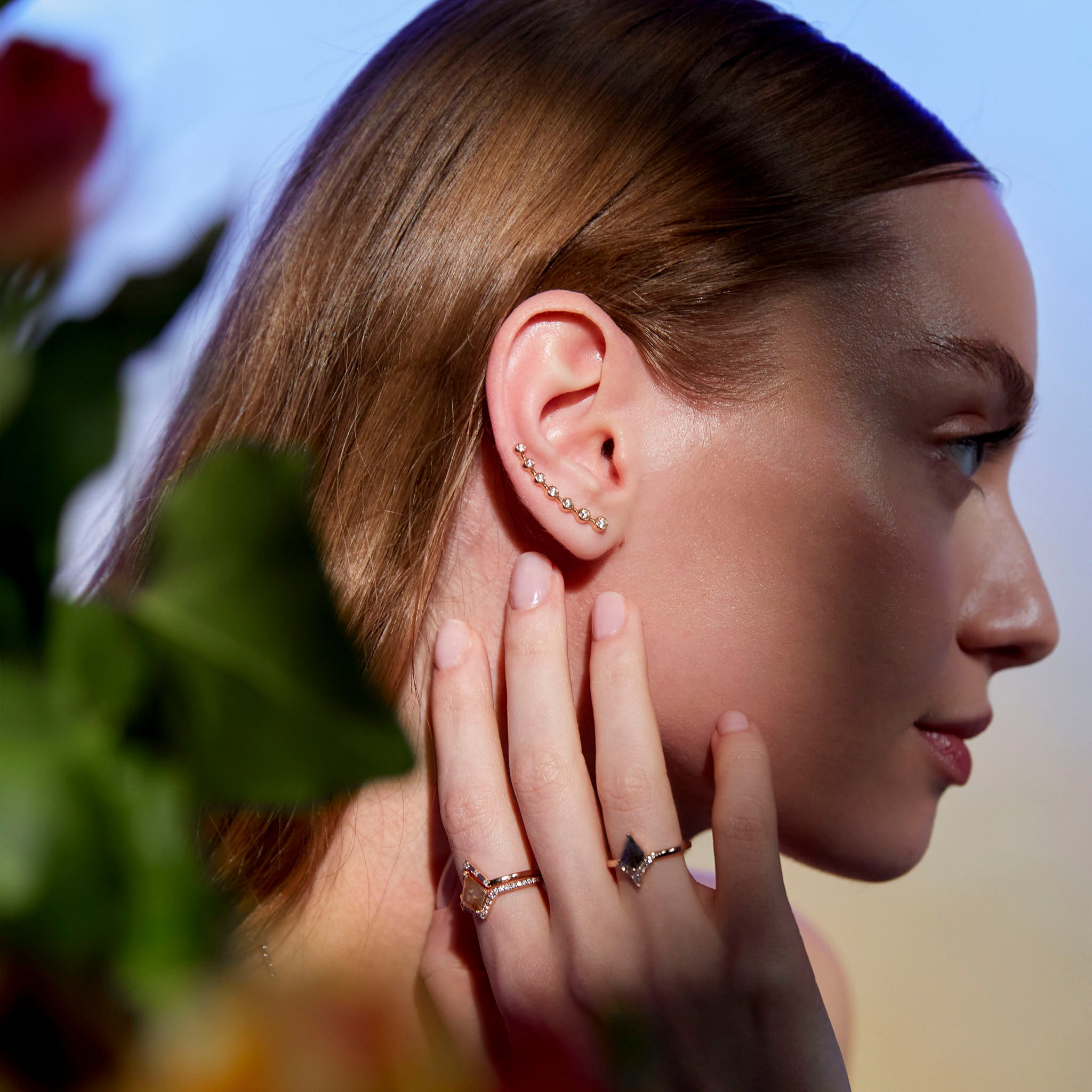 image of a woman's ear wearing a gold ear-crawler earring adorned with white diamonds.