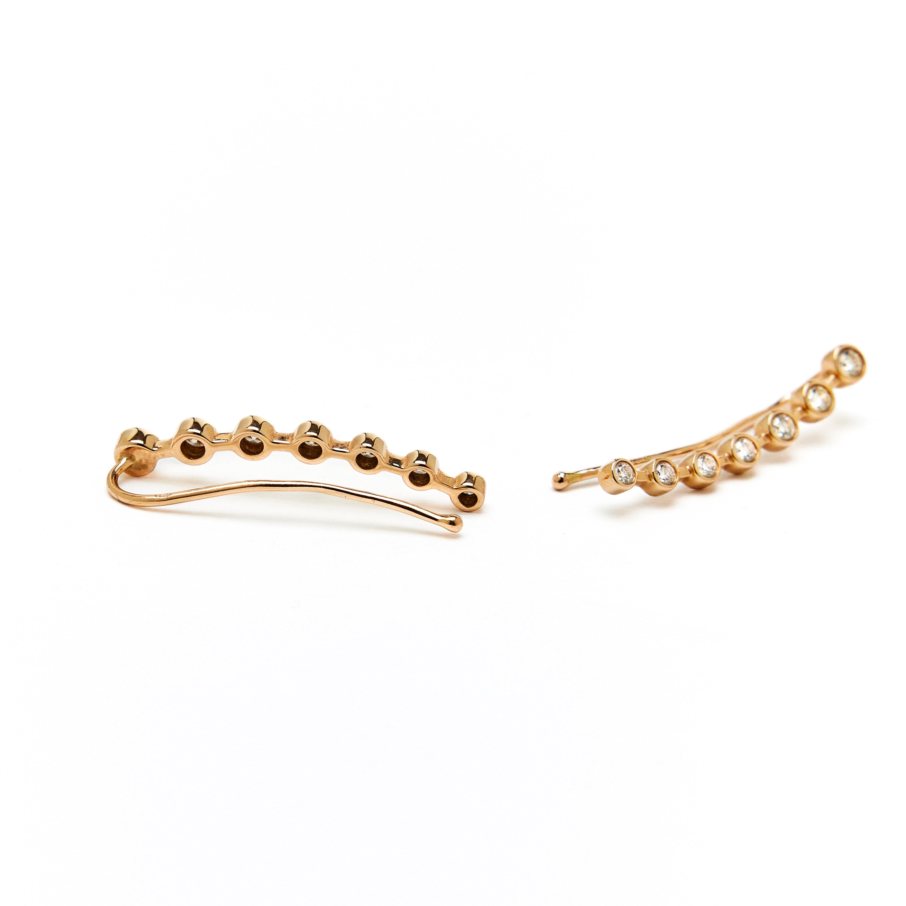 gold ear-crawler earrings adorned with white diamonds.