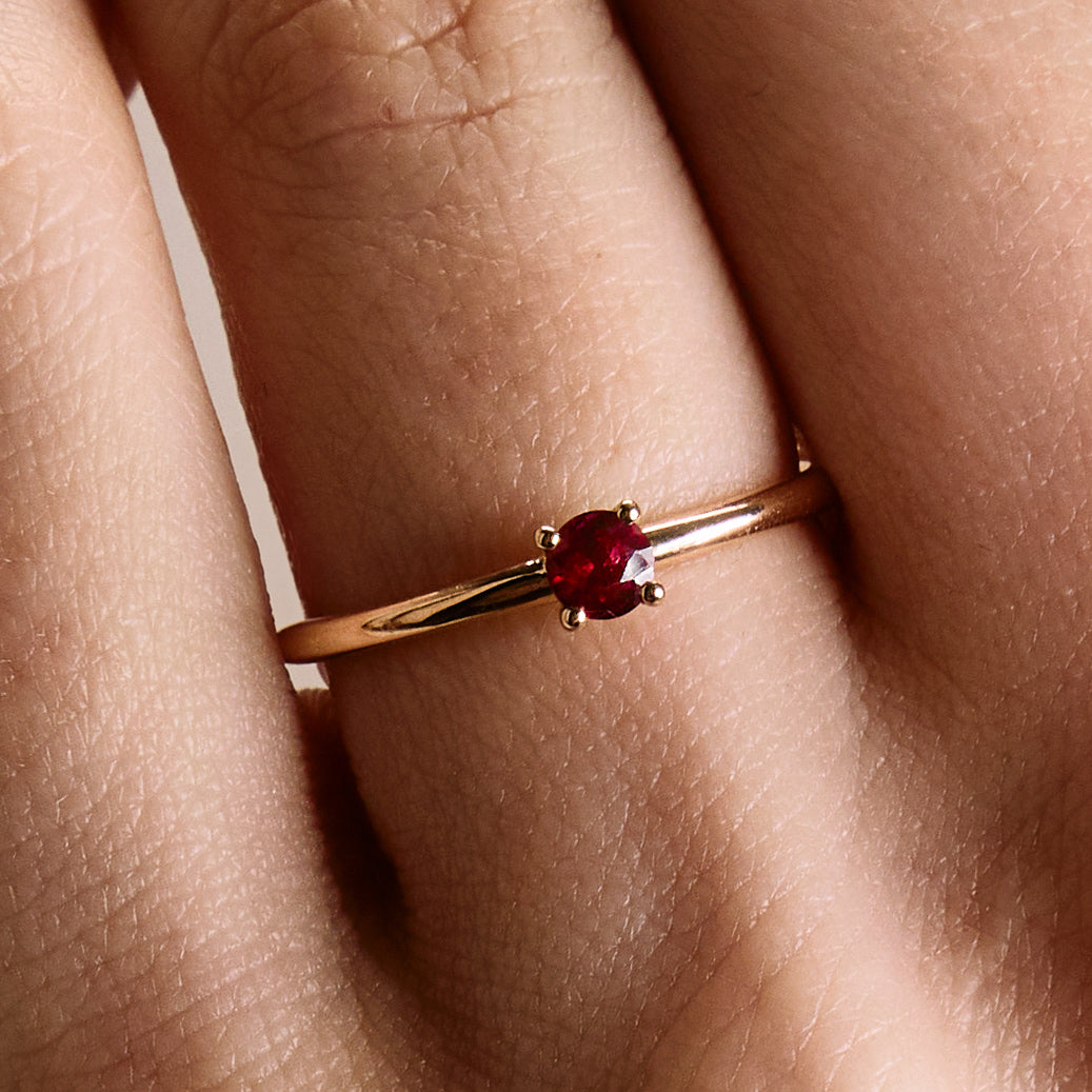 gold ring with a small cute ruby on a hand.
