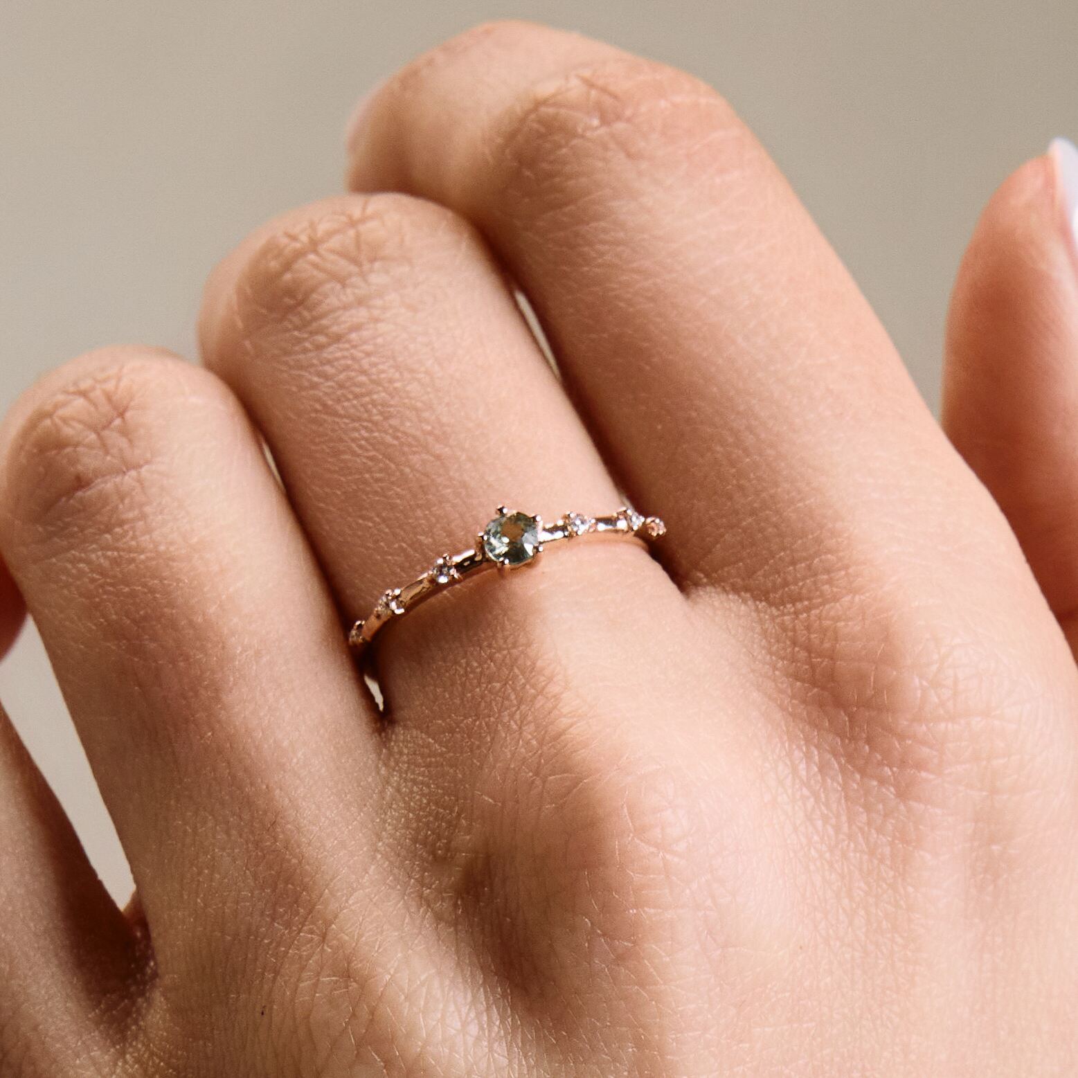 A gold band ring featuring a central sapphire with smaller diamond accents around it, presented on a a hand