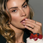 beautiful woman eating fruits off a cake, wearing the most elegant eternity white diamonds and black diamonds rings, looking straight at the camera
