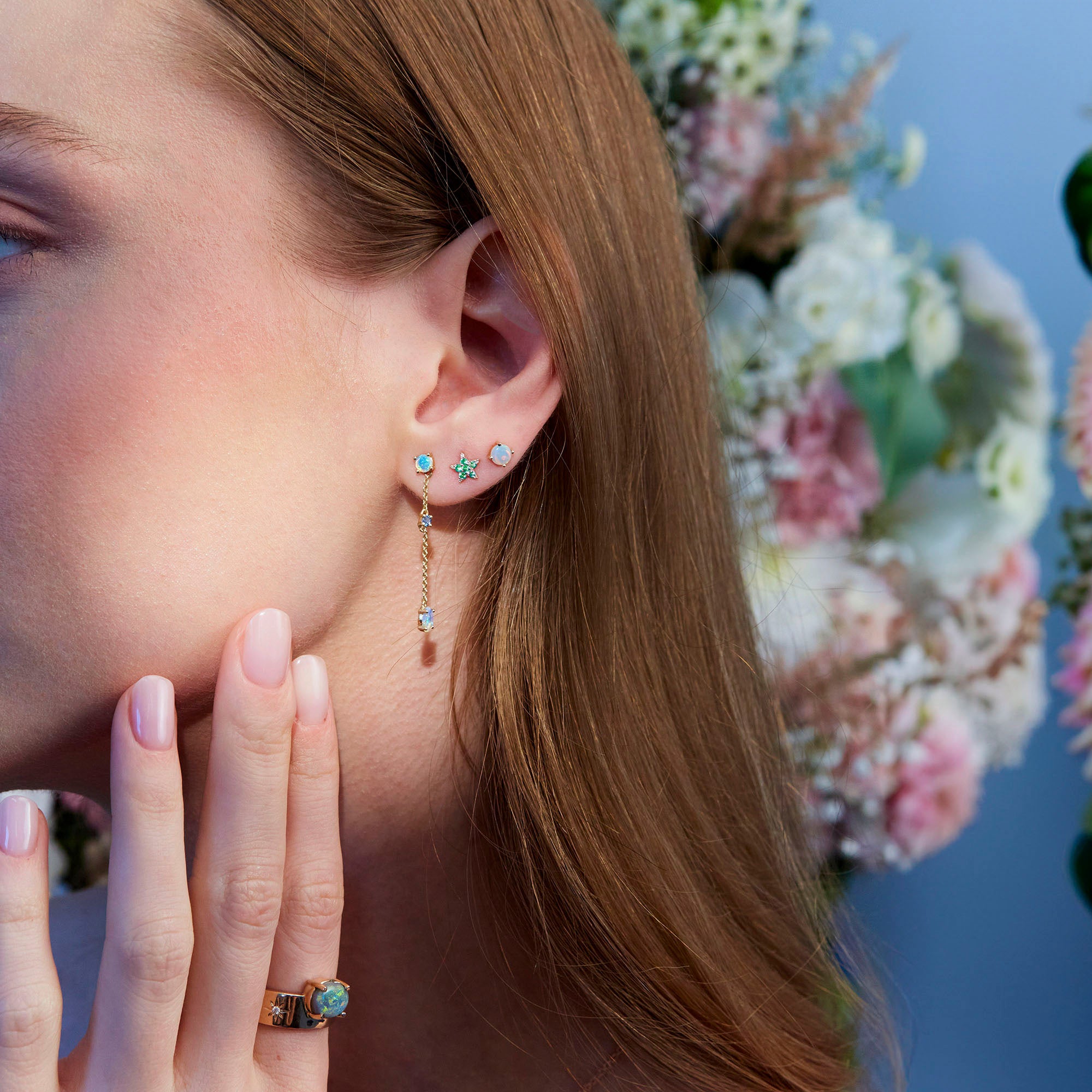 green blue shade stones earrings, emeralds, sapphires ansd emeralds, on a models ear.