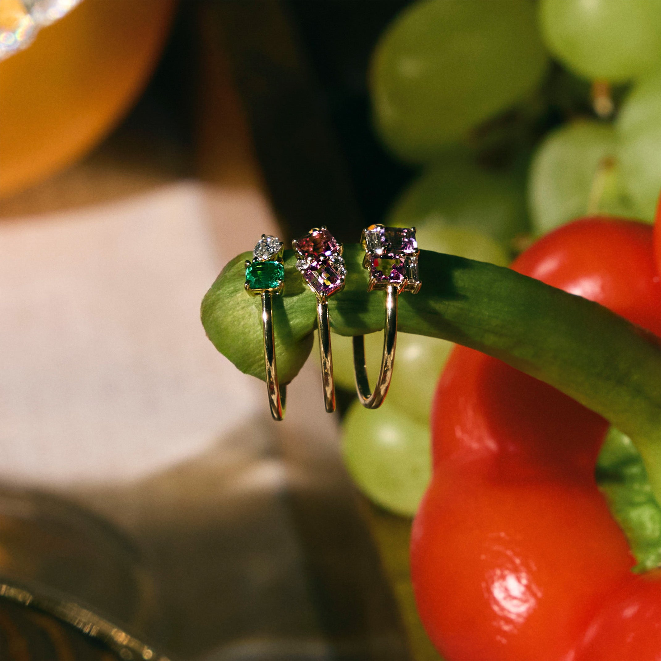 Rose gold toi et moi ring with an emerald and a diamonds, cluster sapphire and diamonds ring and diamonds and sapphire square ring, on a pepper.  