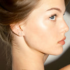 Close-up of a woman's profile with a focus on her earrings, a flash shape earring and a floating dot diamond earring.