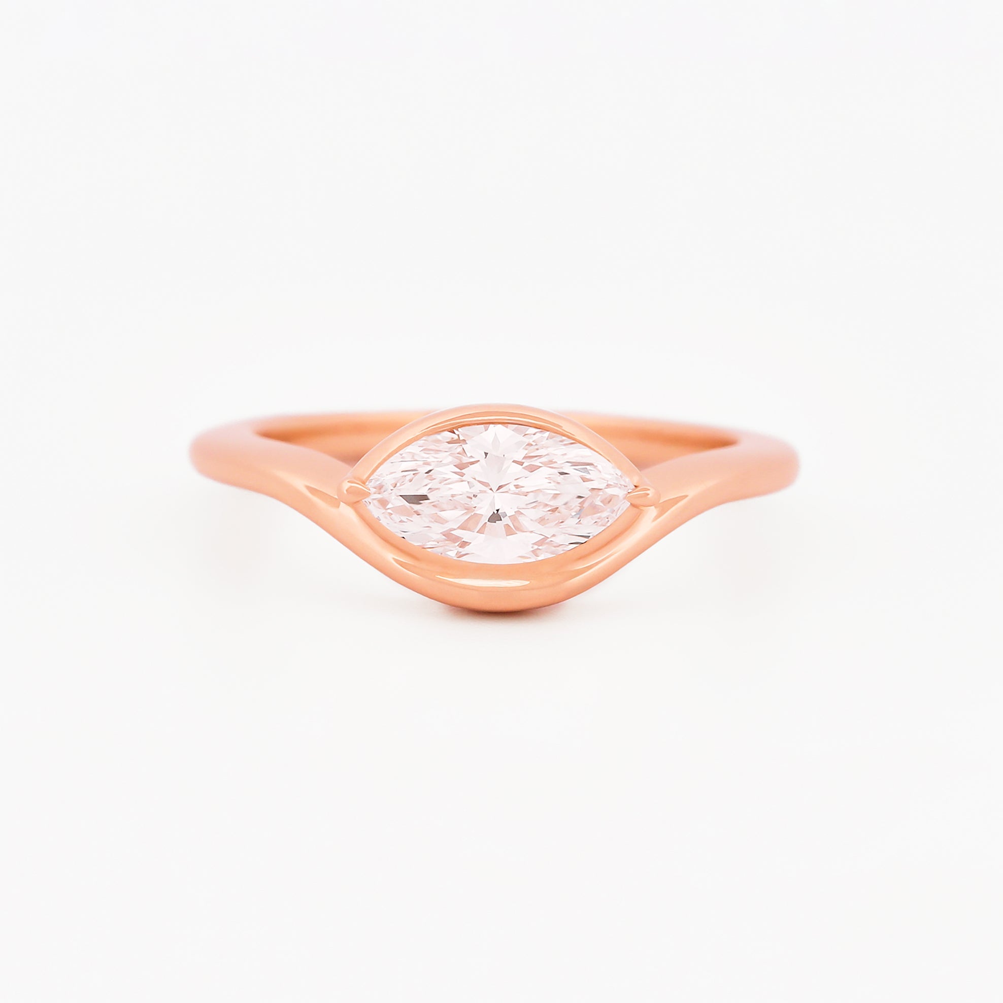 Rose gold solitaire ring with a marquise diamond on a white background.