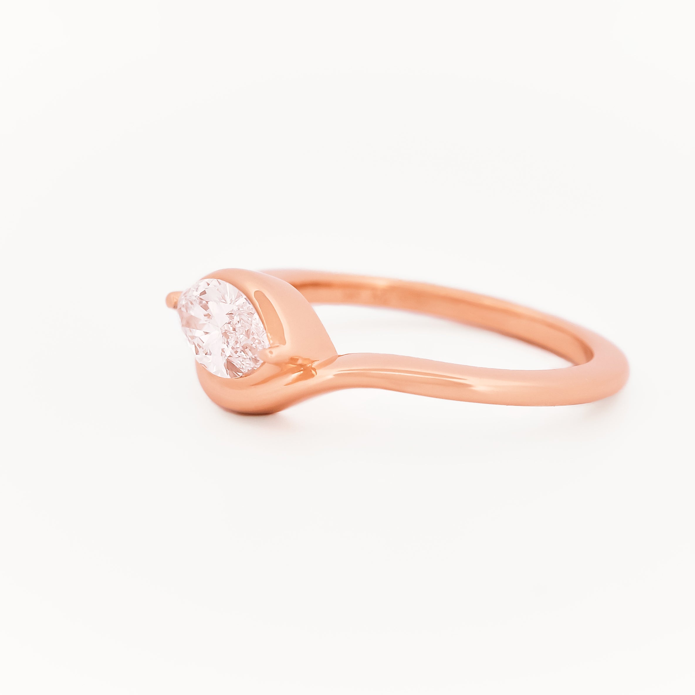 Rose gold solitaire ring with a marquise diamond on a white background