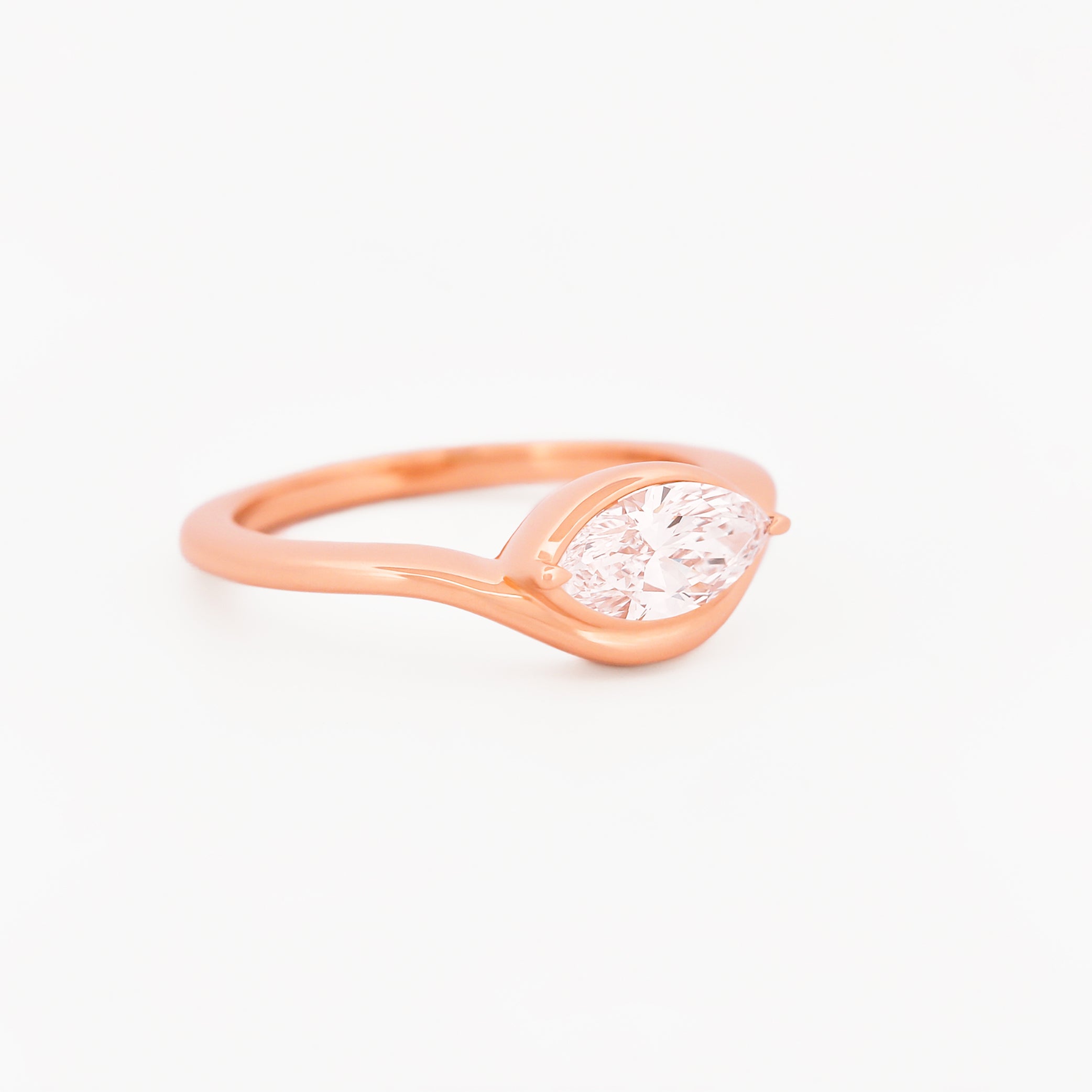 Rose gold solitaire ring with a marquise diamond on a white background