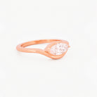 Rose gold solitaire ring with a marquise diamond on a white background