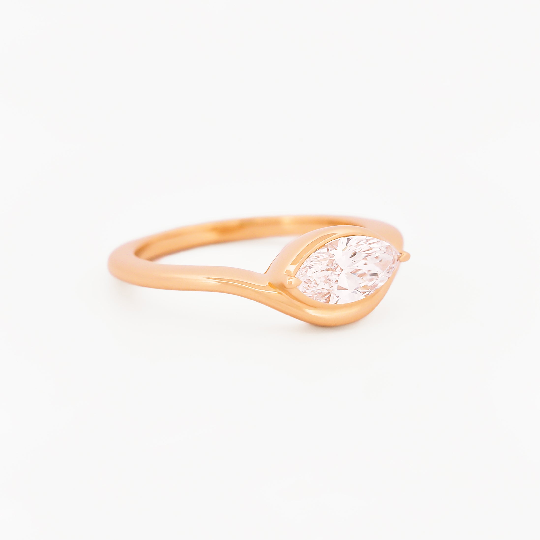 Yellow gold solitaire ring with a marquise diamond on a white background
