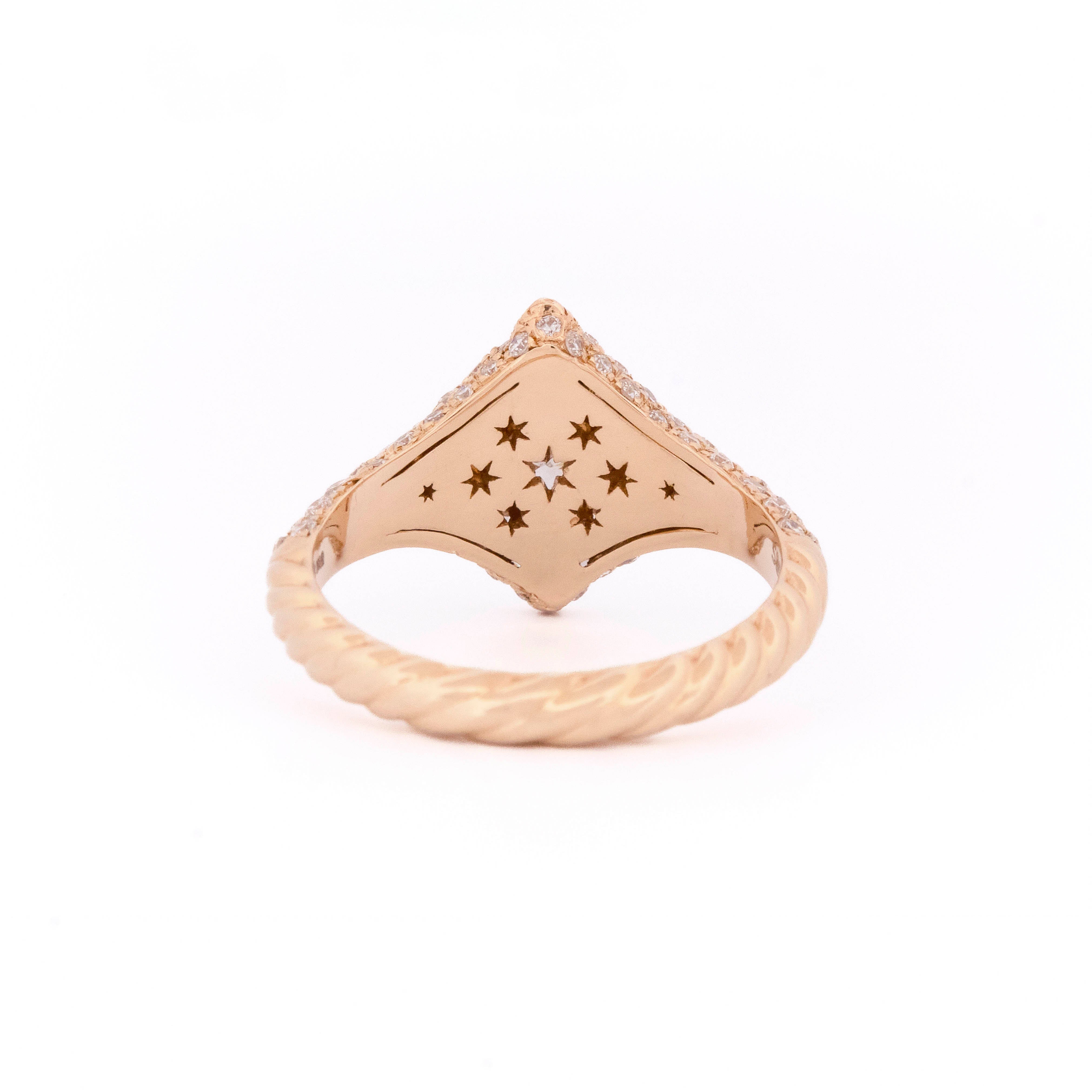 Gold ring with star design on back a white background