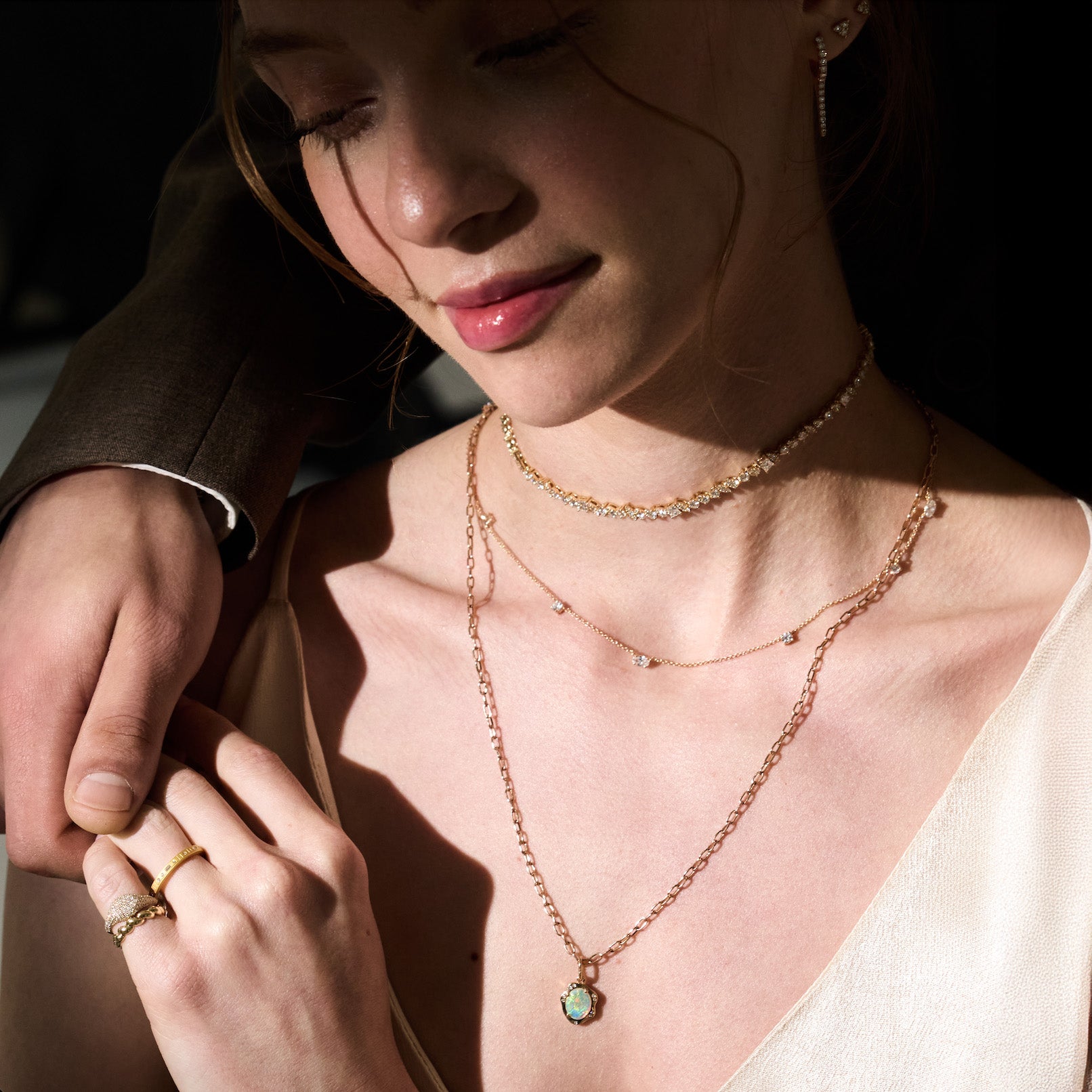Woman wearing multiple gold necklaces with a close-up of her hand and jewelry.