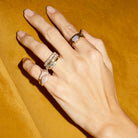 Hand wearing multiple rings on a mustard yellow background