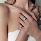 A woman wearing a ring with a australian opal and diamonds, two pinky ring with marquise diamonds set in curvy rose gold bands. 
