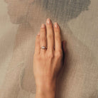 Hand wearing a rose cut diamond ring on a textured beige background.