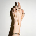 Hand wearing multiple gold rings with precious stones, and bracelets on a white background