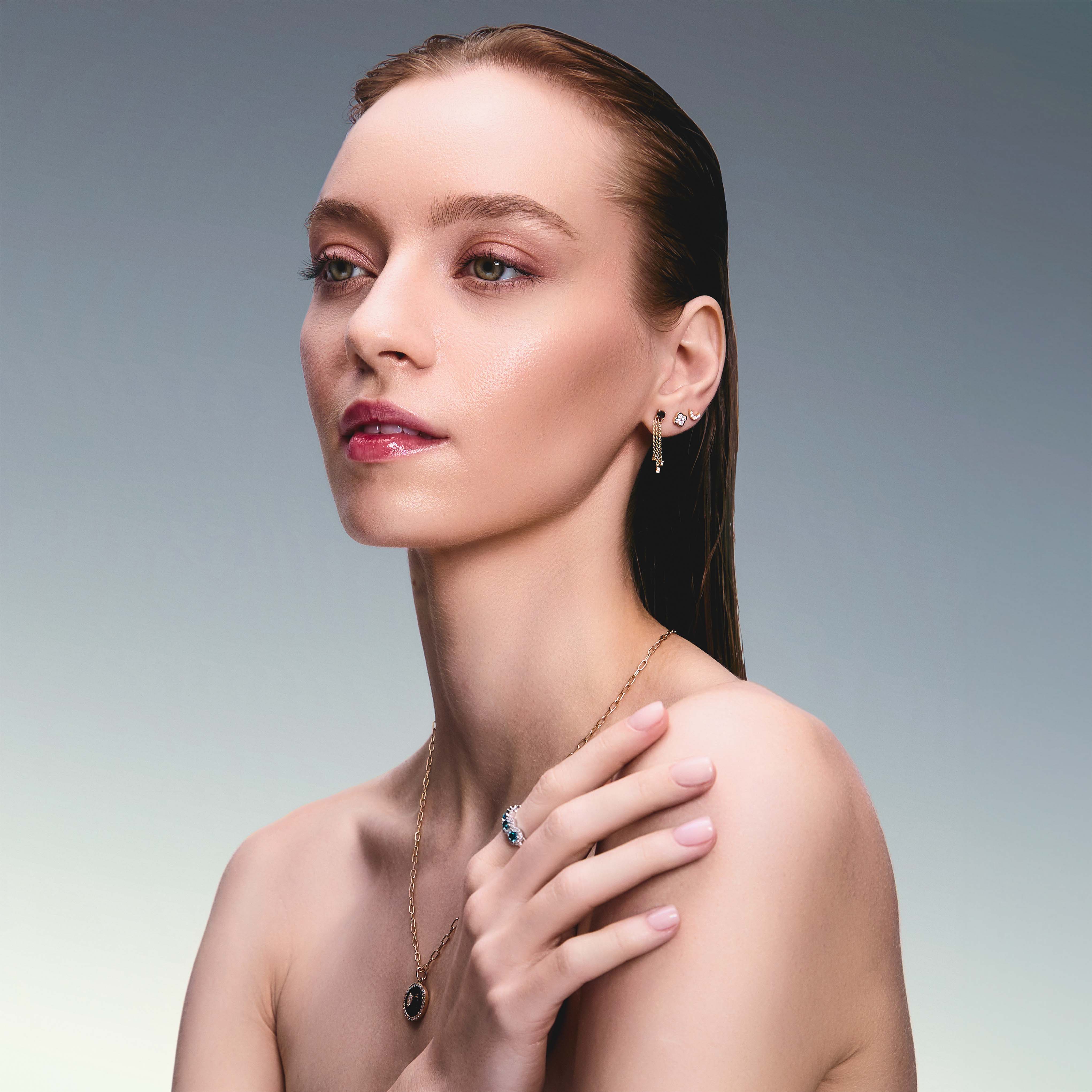 Beautiful model wearing some incredible stud earrings, one is a trilik hanging earring with black diamonds, the second earring is a diamond clover and the third earring in a diamond new moon. 