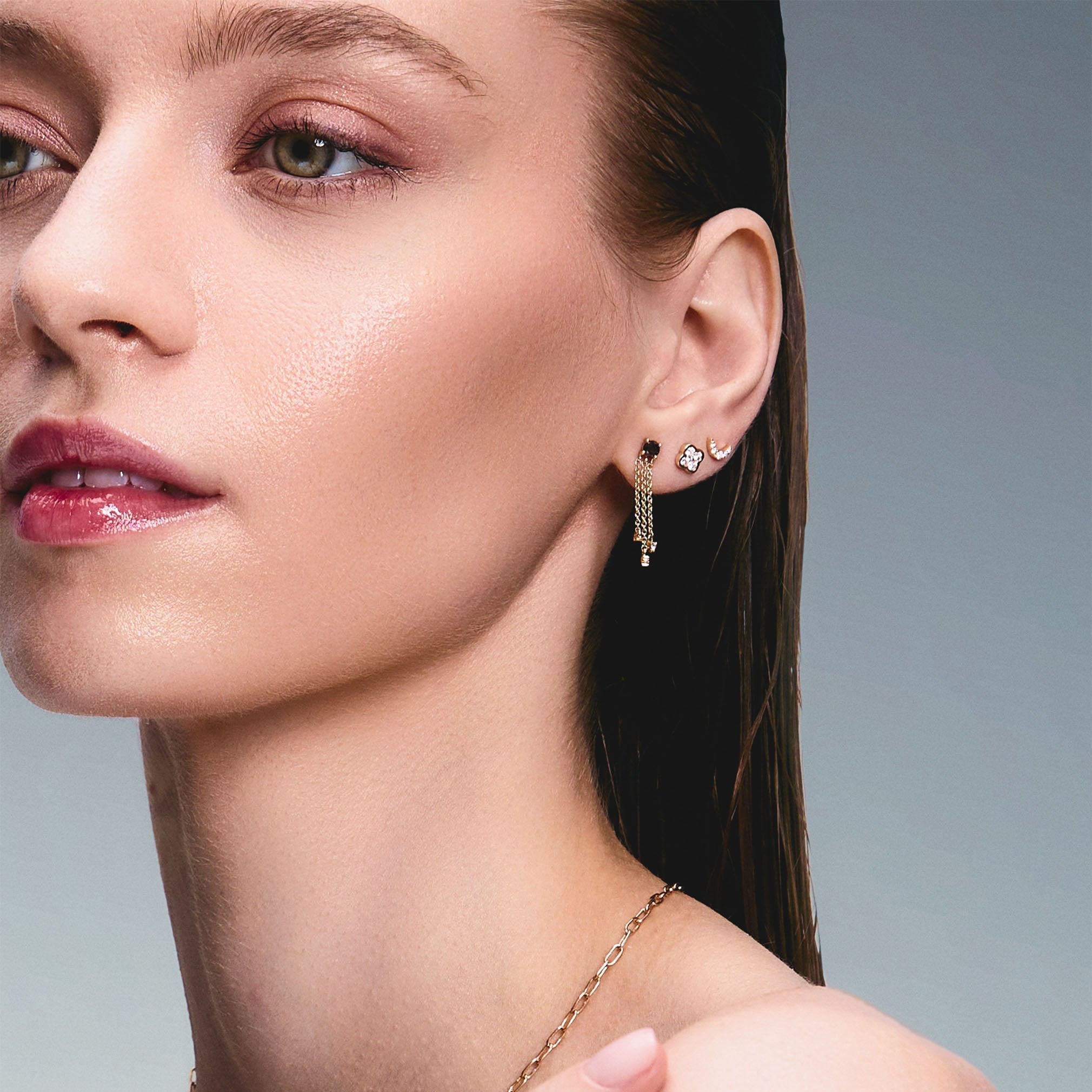 Beautiful model wearing some incredible stud earrings, one is a trilik hanging earring with black diamonds, the second earring is a diamond clover and the third earring in a diamond new moon. 