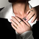 Close-up of hands wearing multiple rings with a neutral background