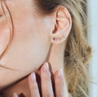 beautiful blossom flower earrings on model, diamond earrings simple arranged in a game of three dots.