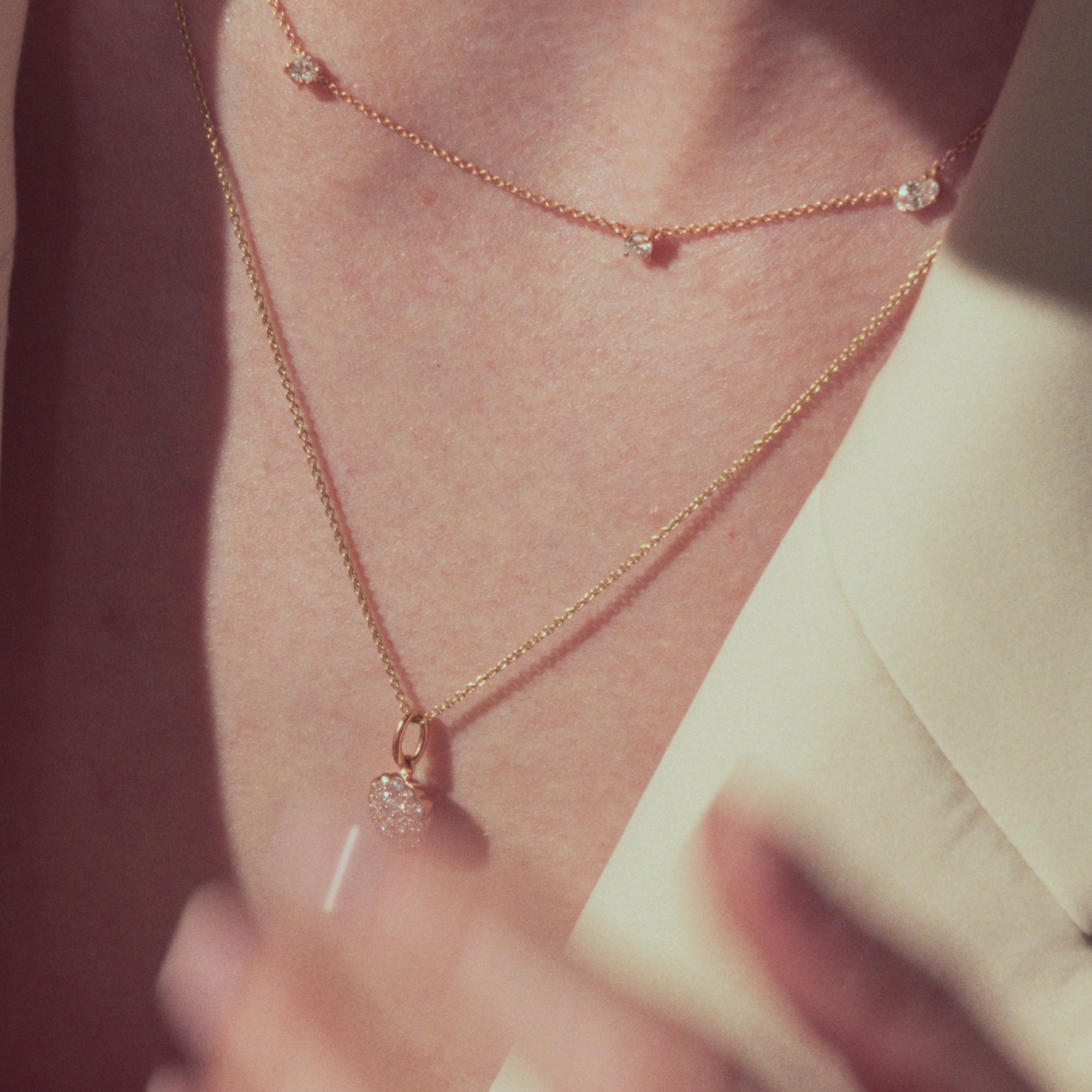 Rose gold necklaces, one with scattered diamonds, and one with a round diamonds flower pendant on a model