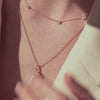 Rose gold necklaces, one with scattered diamonds, and one with a round diamonds flower pendant on a model